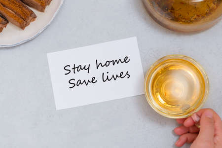 Stay home, save lives motivation phrase on white note with tea and sweets. Self-isolation motivationの写真素材