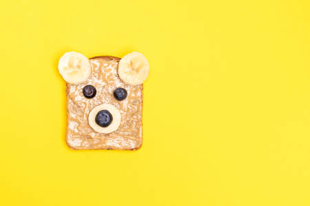 Funny children breakfast toast with peanut butter in a shape of bear with blueberry and banana on...