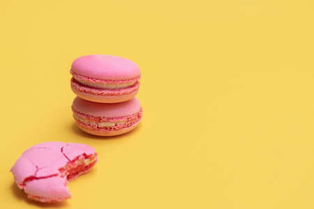 Stack of pink macaroons on yellow background. Colorful almond cookies. Pastel cake macarons background with copy spaceの写真素材