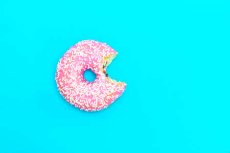 Top view of bitten glazed donut on blue background with copy spaceの写真素材