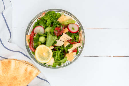 Above view of Middle Eastern Pita Salad (Fattoush Salad) on white wooden table with copy spaceの写真素材