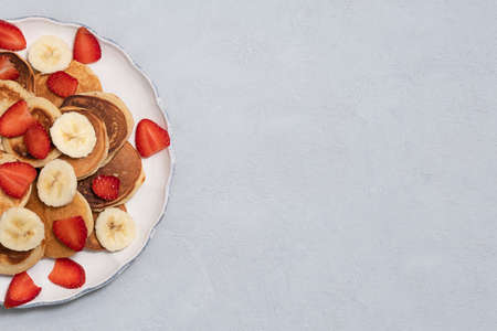 Homemade tiny pancakes on white plate on neutral concrete background. Image with copy space, top...