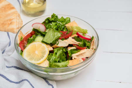 Fattoush pita bread salad in a glass bowl on white wooden tableの写真素材