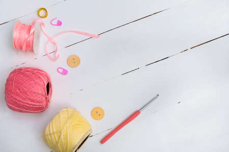 Crochet yarn background with yarn, crochet hook, accessories on white wooden background. Handmade crocheting crafts. Top view with copy spaceの写真素材