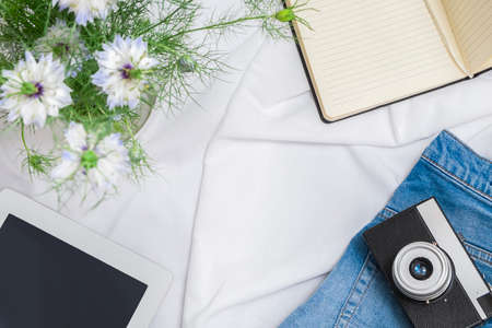 Frame set of beauty blogger or influencer accessories with tablet, vintage camera, paper notebook, flowers, blue jeansの写真素材