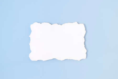 White empty blank paper with uneven border on light blue background. Invitation card mockup on soft...