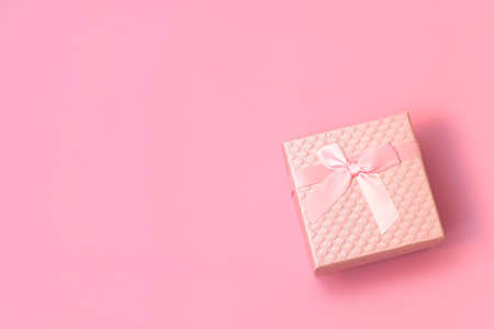 Top view of pink gift box with satin bow on pastel pink background with copy space. Flat lay composition for Wedding, Birthday, Happy womans day, Mothers Day, Valentines Day.の写真素材