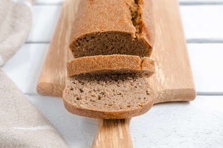 Homemade sourdough rye bread sliced on a cutting board on white table, close-up image, selective...