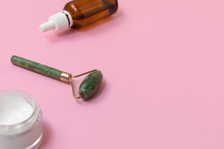 Jade face roller for beauty facial massage therapy. Beauty tools on pastel pink background with copy spaceの写真素材