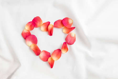 Top view of heart made of pink rose petals on white bed sheets on honeymoon. Surprise romantic concept background stock photo...の写真素材