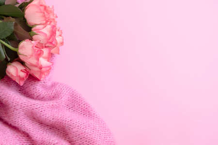 Gentle, romantic, feminine background with beautiful roses bouquet and knitted blanket on pastel pink backgroundの写真素材