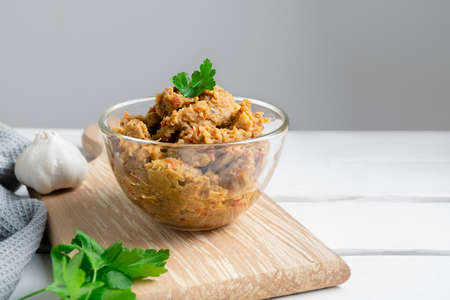 Traditional Balkan dish Kiopoolu, eggplant based spread in a glass bowl on wooden cutting board on...