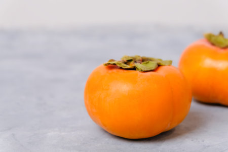 Closeup of ripe persimmon fruits on neutral light background with copy spaceの写真素材