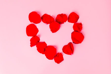 Heart made of rose petals on pink background. Romantic conceptの写真素材