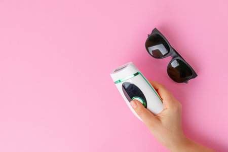 Top view of a womans hand holding at home epilator with glasses on pastel pink background, copy spaceの写真素材