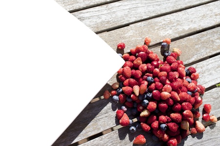 crop of wild strawberry and bilberry with white plate
