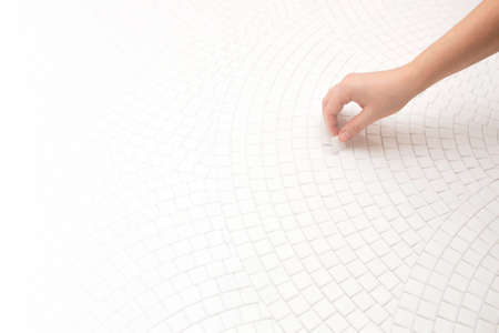 Hand with mosaic, making mosaic decor. White gradient background for text.の写真素材