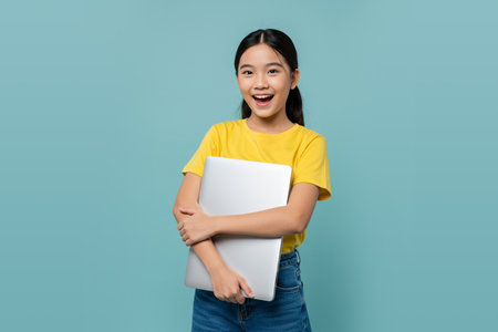Smiling Asian Girl Holding a Laptop Education and Technology Conceptの素材
