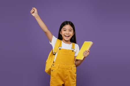 Cheerful Asian Student Raising Hands with Notebookの素材
