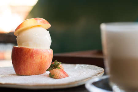 sweet vanilla ice cream in half of apple and little strawberryの写真素材