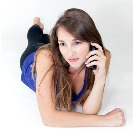 young woman on the phone lying on white backgroundの写真素材