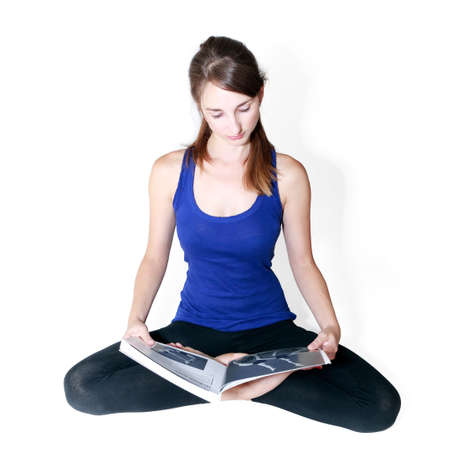 Young woman reading a book of yoga on white backgroundの写真素材