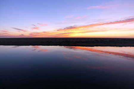 Sunset reflection in a puddle of oceanの写真素材