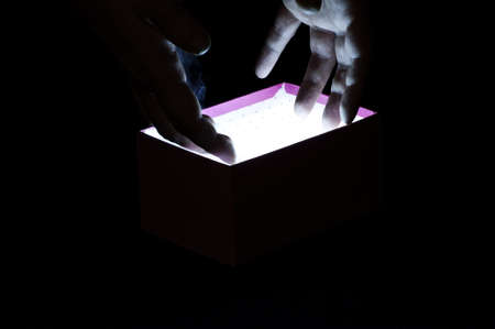 Hand reaching into a magic box on blackの写真素材