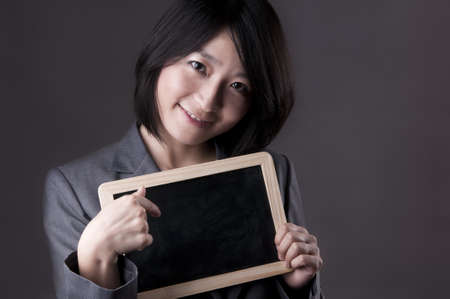 Happy woman in suit pointing to blackboardの写真素材