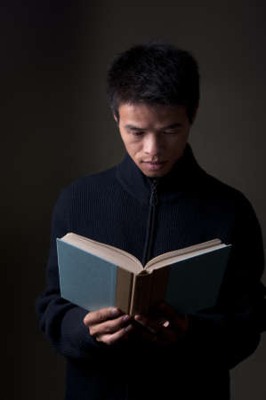 Chinese college student reading a book in sweaterの写真素材