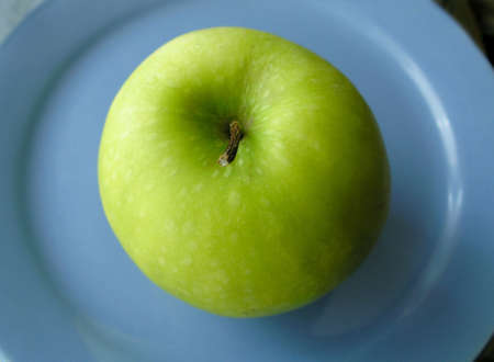 Green apple on blue plateの写真素材