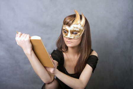 Pretty young woman in Venetian mask with book
の写真素材