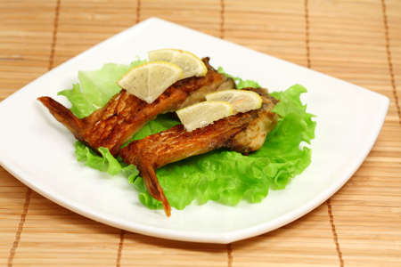 Roasted fresh bream with lemon and lettuce on a plateの写真素材