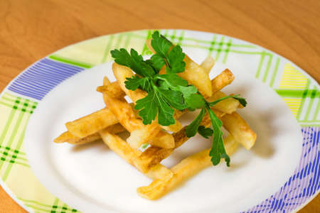 Fried potato on ceramical plate with parsley leaf