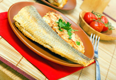 Baked sea fish with parsley on a plateの写真素材