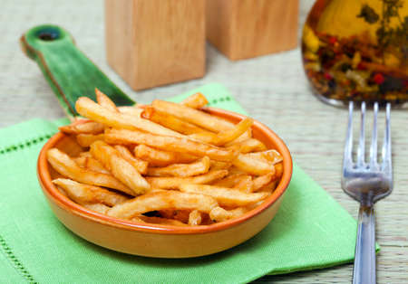 Fried potato on ceramical plate and oil and fork