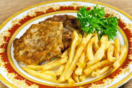 Fried potatoes with meat cutlet and parsley on a plateの写真素材