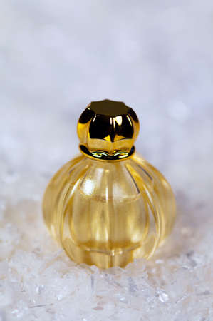 Perfume in golden color on white snow background