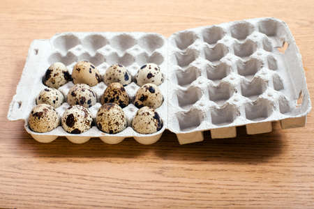 Quail's eggs in  cardboard box on wooden table