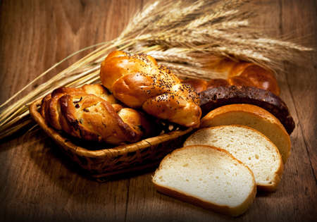 Fresh baked traditional bread with wheat in basket on wooden table
 
