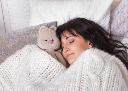 Girl sleeps in a bed with a toy a teddy bear