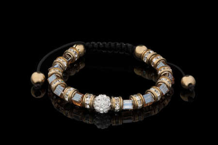 Bracelet made of beads with rhinestones on a black lace, photo on a black backgroundの写真素材