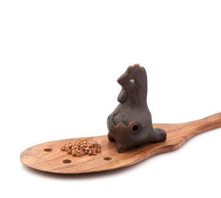 Clay whistle on a wooden spoon with buckwheat groatsの写真素材