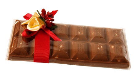 bar of chocolate in a transparent gift wrap with red ribbon and flowers decoration isolated on whiteの写真素材