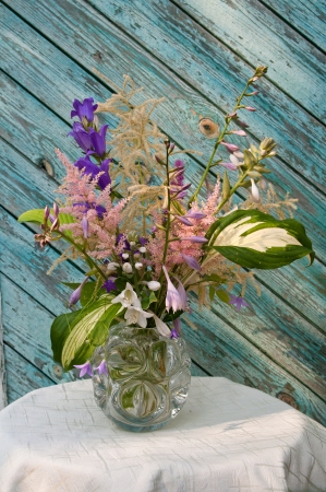 bouquet of wild and garden flowers on a ragged old wooden wall backgroundの写真素材