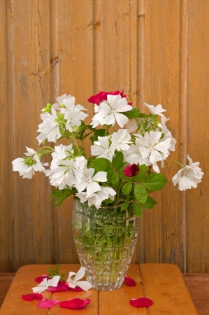 bouquet of white flowers and red roses on the ragged old wooden wall backgroundの写真素材