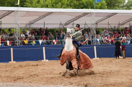 MOSCOW - JUNE 22, 2013 - Times and Epoch festival in the Kolomenskoye. The Middle Ages. - Unidentified horseman galloping on a white stallion covered in ceremonial armor in a historical reconstruction.のeditorial素材