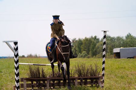 RUSSIA, MOSCOW REGION, DUSHONOVO - JULY 6, 2013 - dushonovskiye maneuvers festival in the Dushonovo village, Moscow Region. - Unidentified horsewoman jumping over barrier on a bay stallion in a historical reconstruction.のeditorial素材