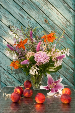 Still life bouquet of hosta, astilbe, hemerocallis, pink hydrangea and nectarines  Nectarines and lily on the table の写真素材