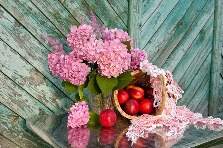still life with hydrangea and basket of nectarines on the old wooden wall backgroundの写真素材